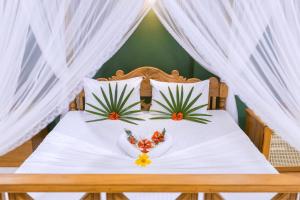 a bed with white curtains and flowers on it at Noeline Villa in Bentota