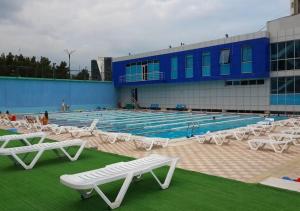 a swimming pool with white tables and chairs in front of a building at Sport time Hotel & Spa in Tbilisi City