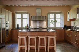 a kitchen with wooden cabinets and a island with bar stools at Villa Valle, Villa Saletta Wine Estate in Forcoli