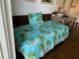 a bed with a blue blanket with palm trees on it at Apartamento parcha in Culebra