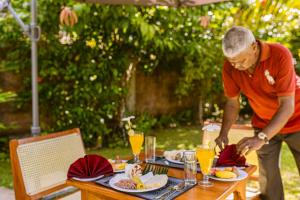 a man standing over a table with food on it at Noeline Villa in Bentota