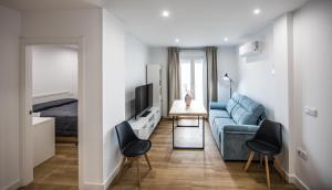 a living room with a blue couch and a bed at Apartamentos Ciudad del Cava in Almendralejo