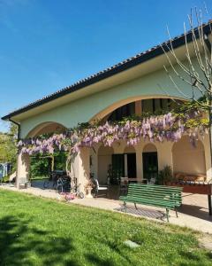 a green bench in front of a building with purple flowers at B&B Ca' Restom in Reggio Emilia