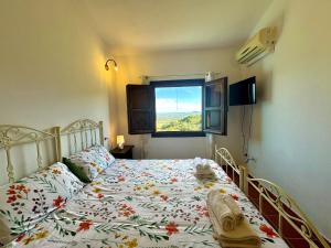 a bedroom with a bed with a floral bedspread and a window at Country Guest House in Cardedu