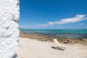 a white chair sitting on a beach near the ocean at Villa Elvira - Apulian Stay Group in Faccia di Trippa +20 photos