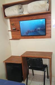 ein Schreibtisch mit einem Fernseher an der Wand in der Unterkunft Pousada Parque in Mostardas