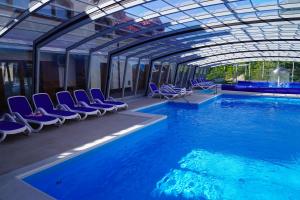 a swimming pool with blue chairs and a building at Apartamenty pod Dębami - noclegi Beskid Niski in Odrzechowa