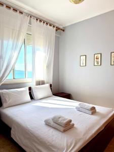 a bedroom with a large white bed with towels on it at ERAL Apart-Hotel & Penthouse in Sarandë