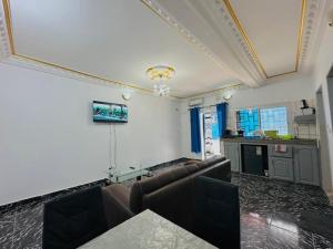 a room with couches and a table and a kitchen at CAMERHOME Carrefour mosqué Cité des palmiers in Douala +64 photos