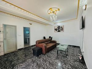 a living room with a leather couch and a table at CAMERHOME Carrefour mosqué Cité des palmiers in Douala
