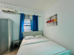 a small bed in a room with a window at CAMERHOME Carrefour mosqué Cité des palmiers in Douala