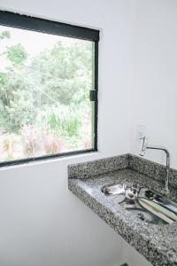 a kitchen sink with a window next to a counter at Pousada do Dione in Delfinópolis +62 photos