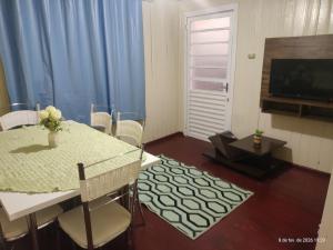 a living room with a dining room table and a television at Casa 2 Quartos - Vila Real in Chapecó