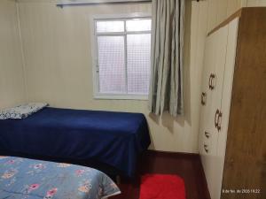 a bedroom with a blue bed and a window at Casa 2 Quartos - Vila Real in Chapecó