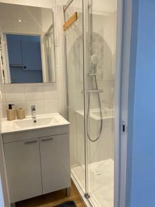 a white bathroom with a shower and a sink at Coquelicot in Waulsort