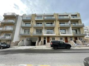a large building with cars parked in front of it at St Julians`s Urban Apartments in Is-Swieqi