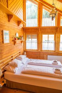 a bed in a room with wooden walls and windows at Four Seasons Lodge in Lackenhof
