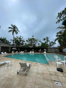 a swimming pool with chairs and a bunch ofitures at Suíte aconchegante beira mar - Suíte 255 in Guarujá