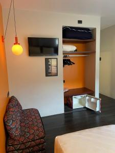 a room with a bed and a chair and a tv at Suíte aconchegante beira mar - Suíte 255 in Guarujá