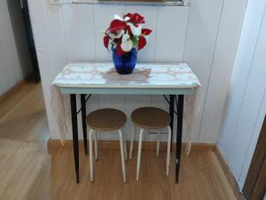 a table with a vase of flowers and two stools at Apartamento para duas pessoas com cama de casal in Teresópolis +7 photos
