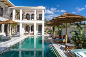 a house with a swimming pool with an umbrella at Villa Riad- וילה ריאד מתחם נופש יוקרתי in Migdal
