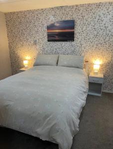 a bedroom with a white bed with two lights on at Seaside Arizona in Morecambe +14 photos