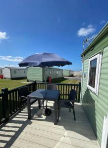 a table and chairs on a deck with an umbrella at Seaside Arizona in Morecambe