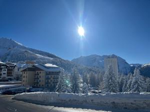 a sun is shining over a city with snow covered trees at Paradiso delle Nevi in Sestriere