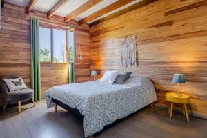 a bedroom with a bed and a wooden wall at Barbadine974, Chalet cosy, 6 personnes, Plaine des Cafres in La Plaine des Cafres