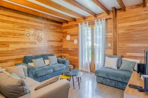 a living room with wooden walls and blue couches at Barbadine974, Chalet cosy, 6 personnes, Plaine des Cafres in La Plaine des Cafres +20 photos