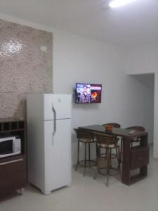 a kitchen with a refrigerator and a table and a tv at Apartamento da Vanda in Ubatuba