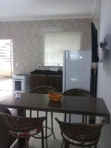 a kitchen with a table with chairs and a refrigerator at Apartamento da Vanda in Ubatuba