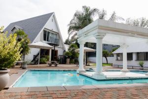 a pool with a gazebo next to a house at St Andrews exclusive guesthouse in Klerksdorp