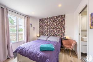 a bedroom with a bed with a purple blanket at Gite de l'artiste in Fay-les-Étangs