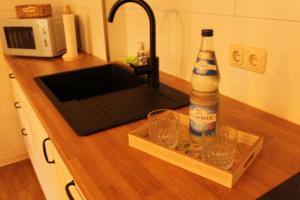 a bottle of beer sitting on a counter next to a sink at Ferienwohnung Annette Mieth in Weitenhagen +12 photos