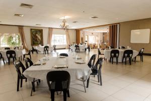 a dining room with white tables and chairs at St Andrews exclusive guesthouse in Klerksdorp