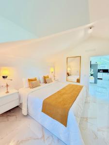 a white bedroom with a large bed and a mirror at Refúgio do Vale Verde in Ponta do Sol