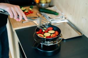 a person is cooking food in a pan on a stove at Cabin stay with optional Donkey Picnic Experience in Hallau +6 photos