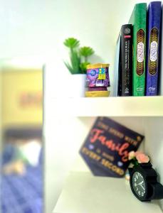 a book shelf with books and a clock on it at RinduTamu Homestay in Lumut