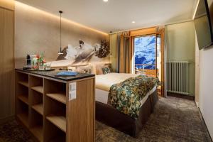 a bedroom with a bed and a desk and a window at Eiger Mürren Swiss Quality Hotel in Mürren