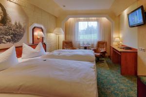 ein Hotelzimmer mit zwei Betten und einem Fernseher in der Unterkunft Hotel Aragon in Ahrensfelde
