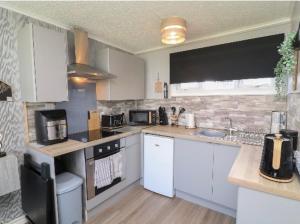 a kitchen with white cabinets and a stove top oven at 106 Cherry park in Chapel Saint Leonards
