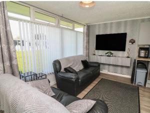a living room with a couch and a flat screen tv at 106 Cherry park in Chapel Saint Leonards