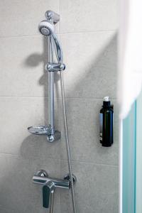 a shower head in a shower with a hose at Azure Apartman Miskolc in Miskolc +7 photos