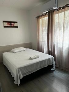 a bedroom with a bed with white sheets and curtains at HL Hotel in Pelotas +11 photos