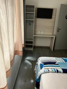 a bedroom with a bed with a television and a desk at HL Hotel in Pelotas