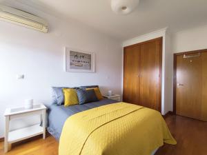 a bedroom with a bed with a yellow blanket at Colinas do Cruzeiro Residence Odivelas in Odivelas