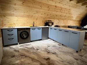 a kitchen with a washing machine and a wooden wall at Kedari Borjomi Cottage in Borjomi