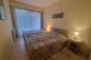 a bedroom with a bed and a window and two lamps at 100 m from the beach prime location in Arcachon