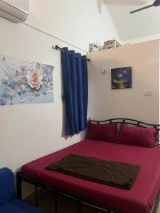 a bedroom with a bed with red sheets and blue curtains at The Wilderness Studio! in Anjuna